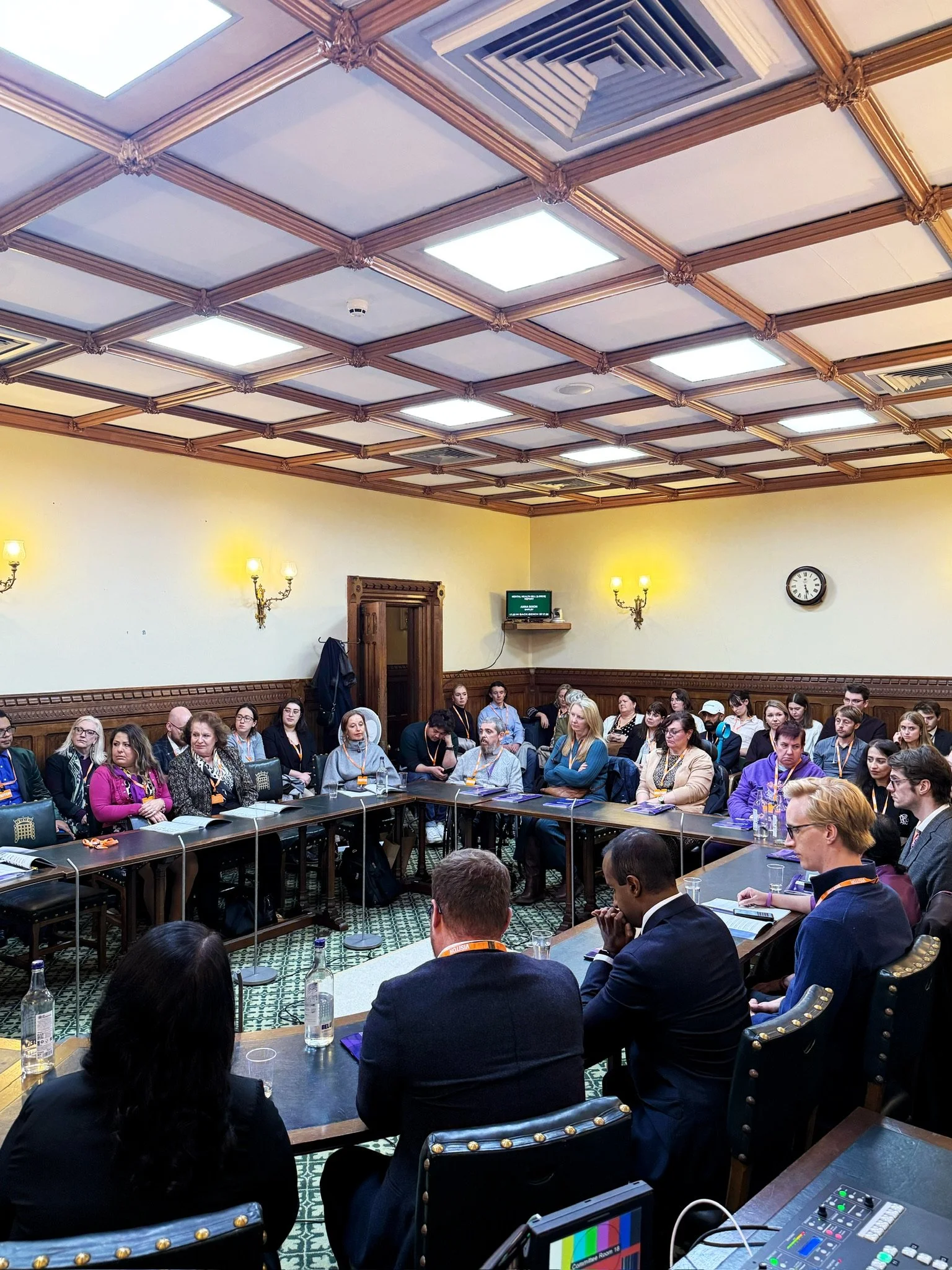 A full room of attendees seated and listening attentively during the report launch event in a parliamentary room, with A Street Transformation reports visible on the tables.