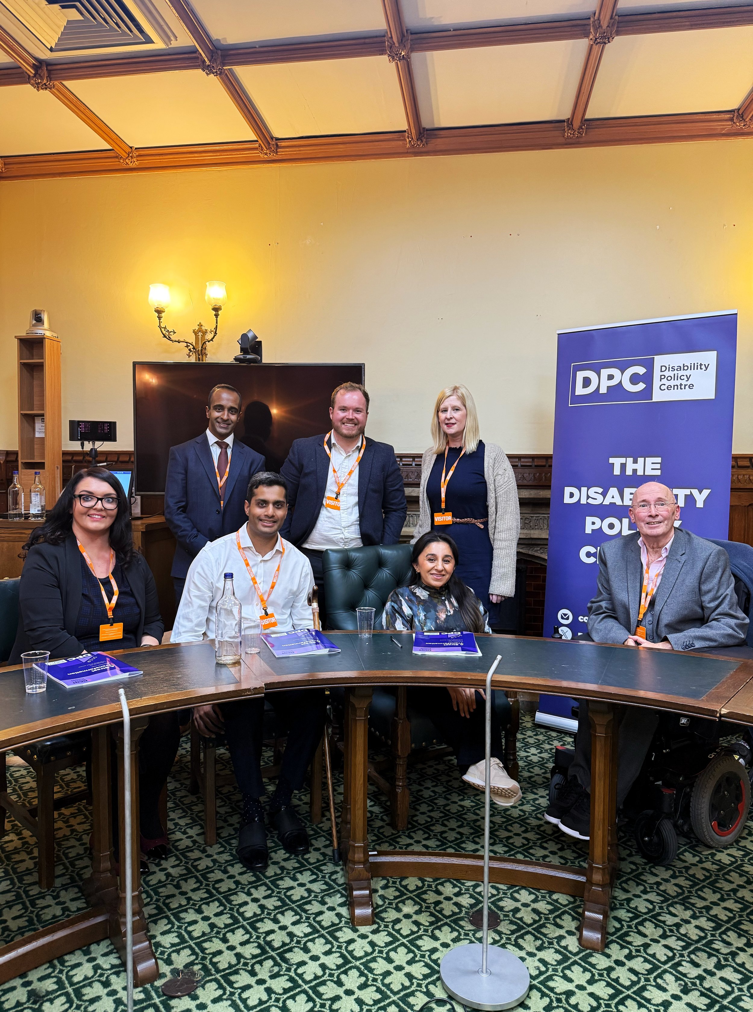 Group photo of event speakers Dr Shani Dhanda, Arun Veerapan, Emma Partlow, Alister Crisp, Louise Connop, and Ian Oakley, taken in a parliamentary room beside a Disability Policy Centre banner.