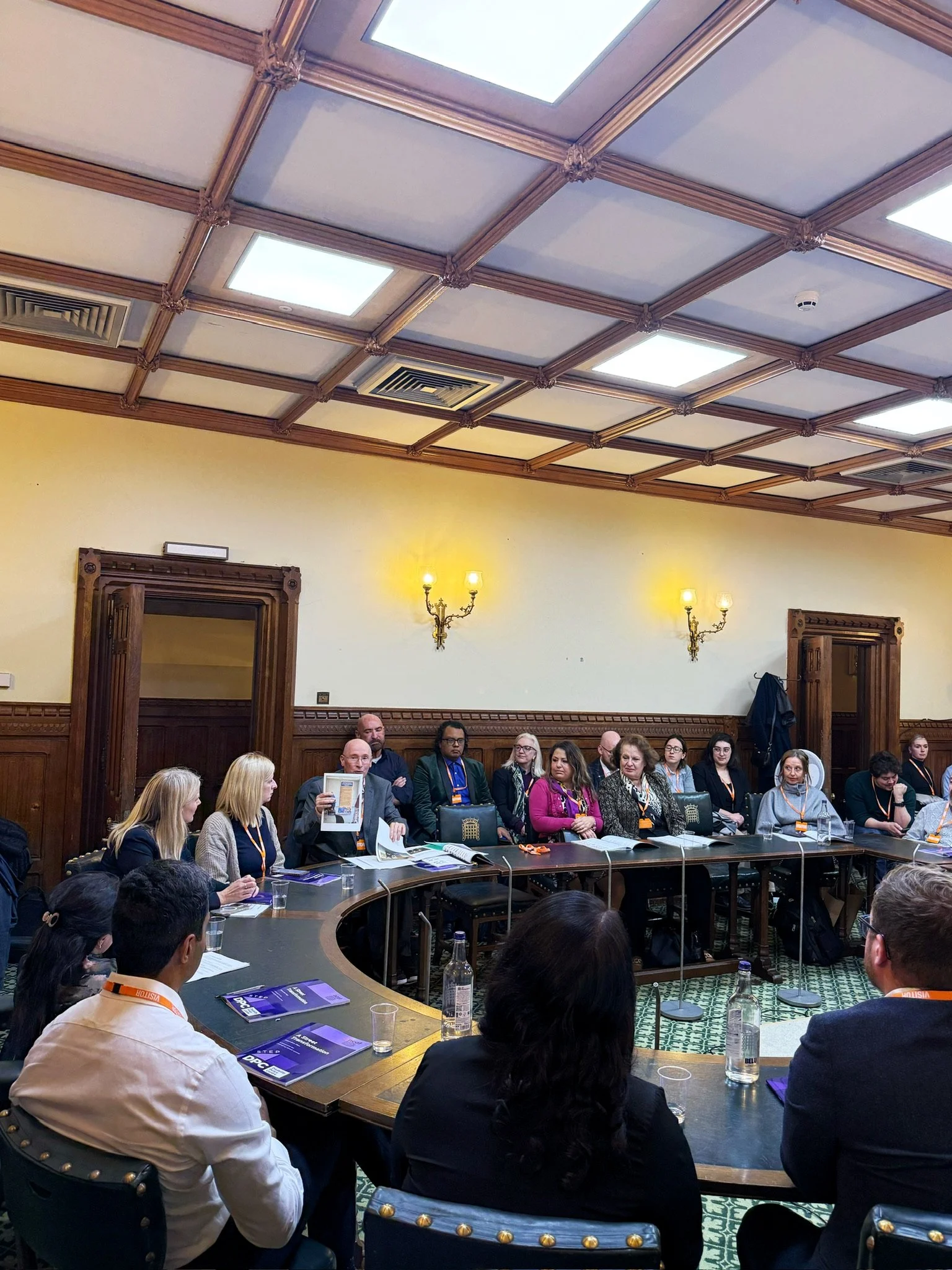 Panel discussion in a parliamentary room hosted by the Disability Policy Centre. At the front, from left to right: Dr Shani Dhanda (chair), Rebecca Paul MP, Louise Connop, and Ian Oakley, Ian is holding up a piece of paper while the audience looks at
