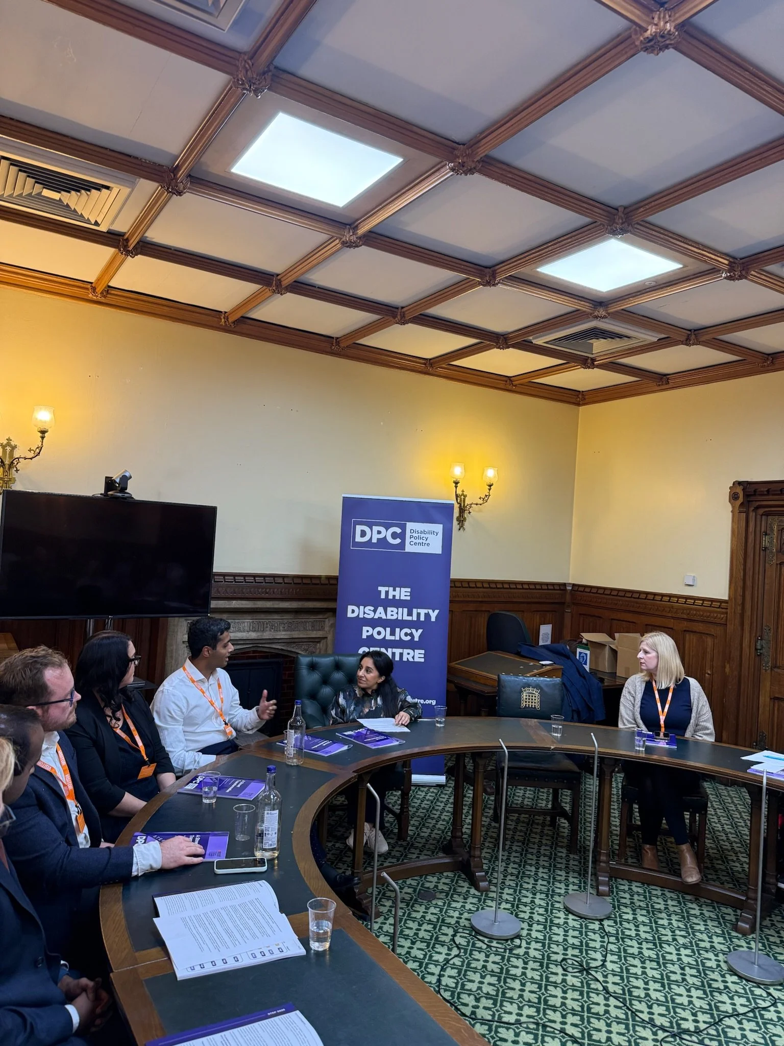 Panel discussion in a parliamentary room hosted by the Disability Policy Centre. At the front, from left to right: Alistair, Emma Paltrow, Arun Veerappan, Dr Shani Dhanda (chair), Rebecca Paul MP and Louise Connop, seated on a round table in front of
