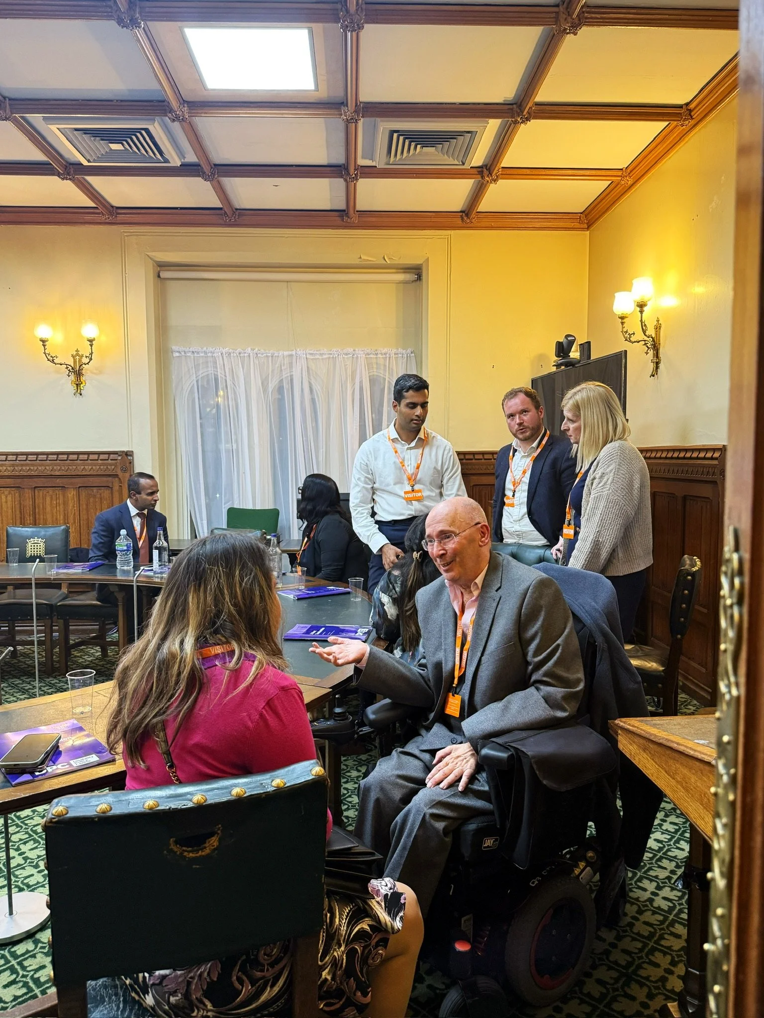 Ian speaking with a guest during the event, while Arun, Alister, and Louise talk in the background inside the parliamentary room.