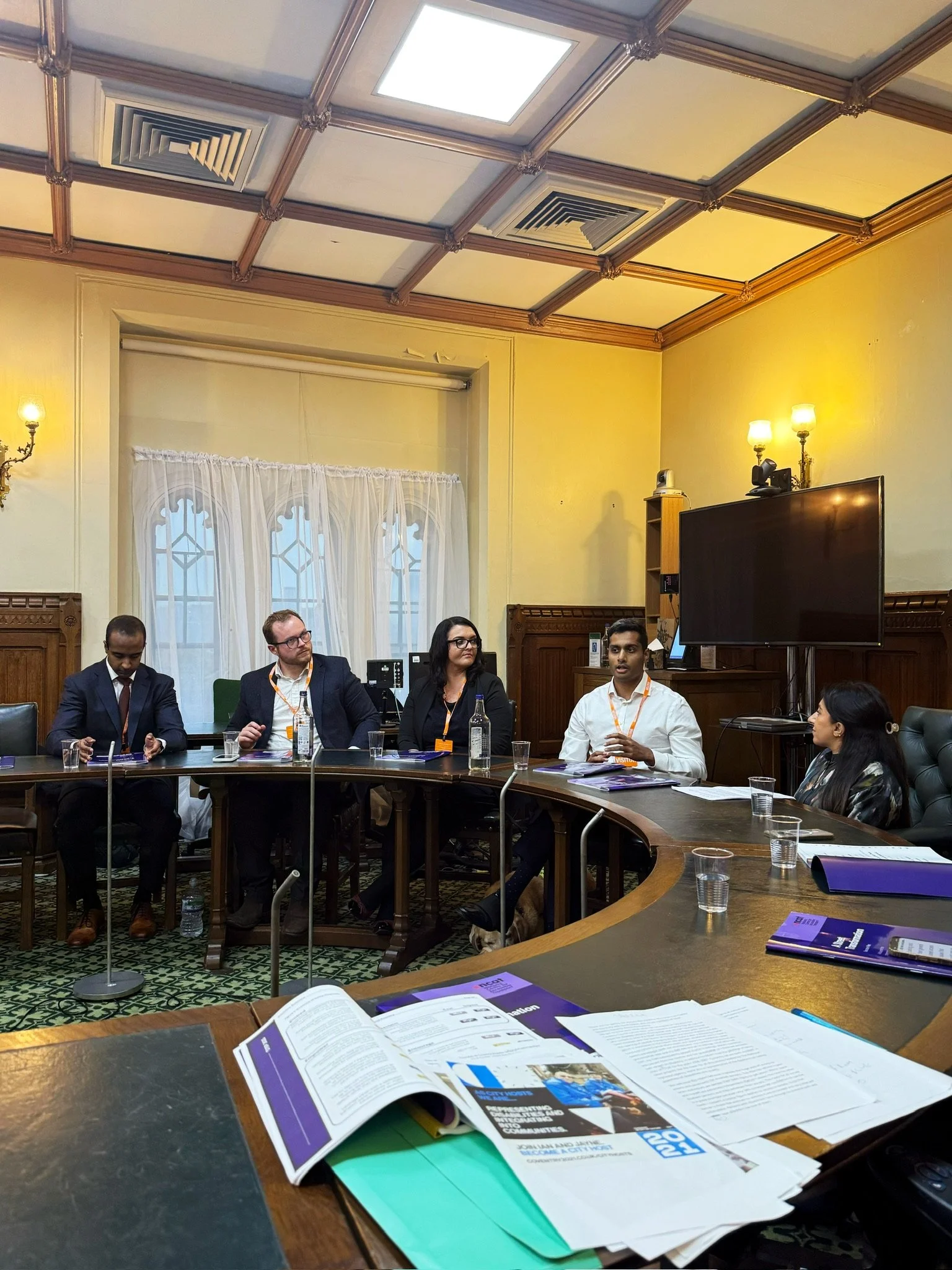 Speaker Arun Veerappan speaking and gesturing while other panelists listen during the discussion. Several A Street Transformation reports are visible on the table in front of them.