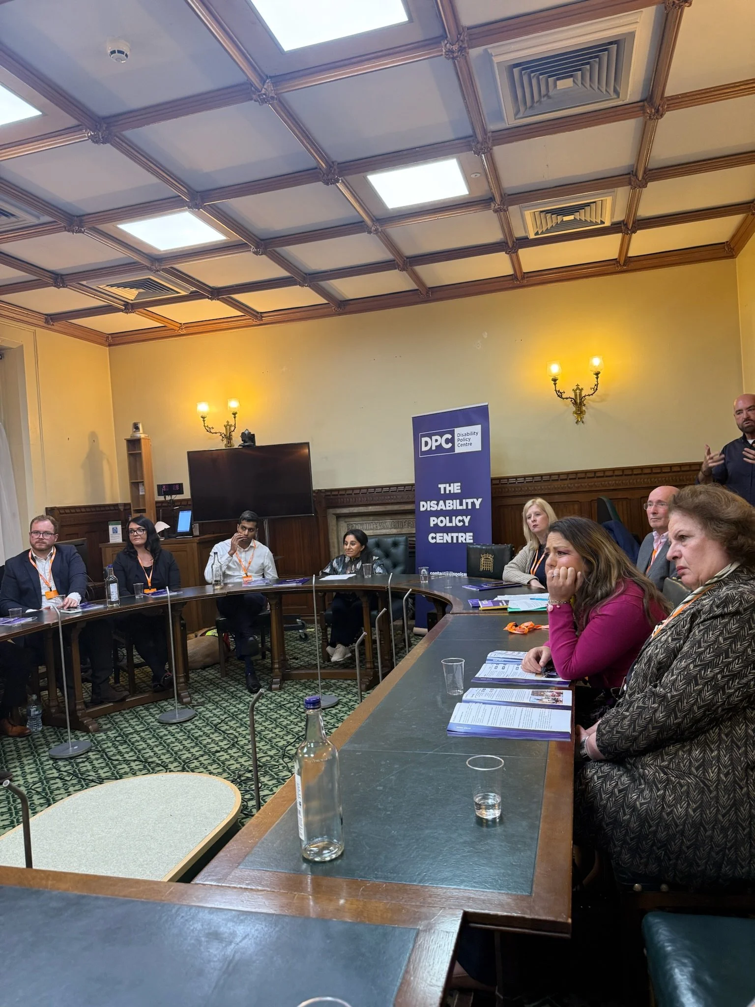 Panel discussion in a parliamentary room hosted by the Disability Policy Centre. At the front, from left to right: Alistair, Emma Paltrow, Arun Veerappan, Dr Shani Dhanda (chair), Rebecca Paul MP and Louise Connop, seated on a round table in front of