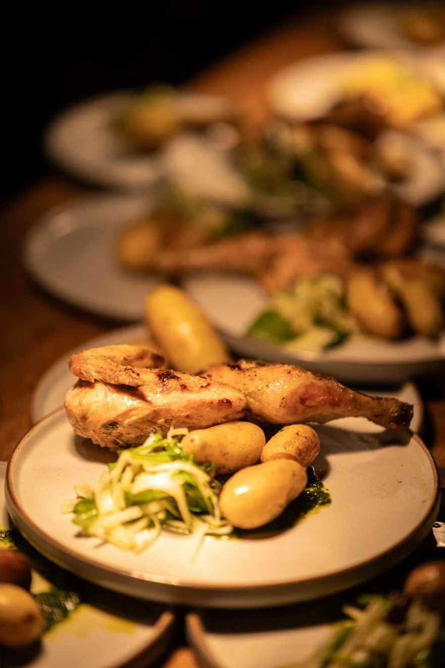Plate with roasted chicken leg, small potatoes, and sliced vegetables.