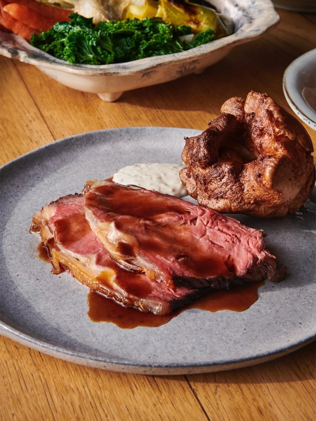Beef cooked low and slow over the fire, picking up smoke as it goes. Potatoes crisped in the dripping. Yorkshires that arrive still rising. Seasonal greens, gravy by the jug, and the kind of plate that lands with a bit of weight to it.

This is what 