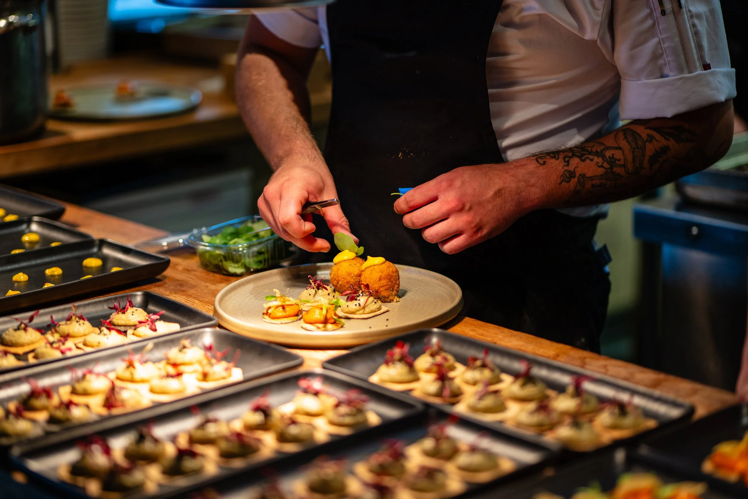 Chef preparing plated appetizers in a professional kitchen.