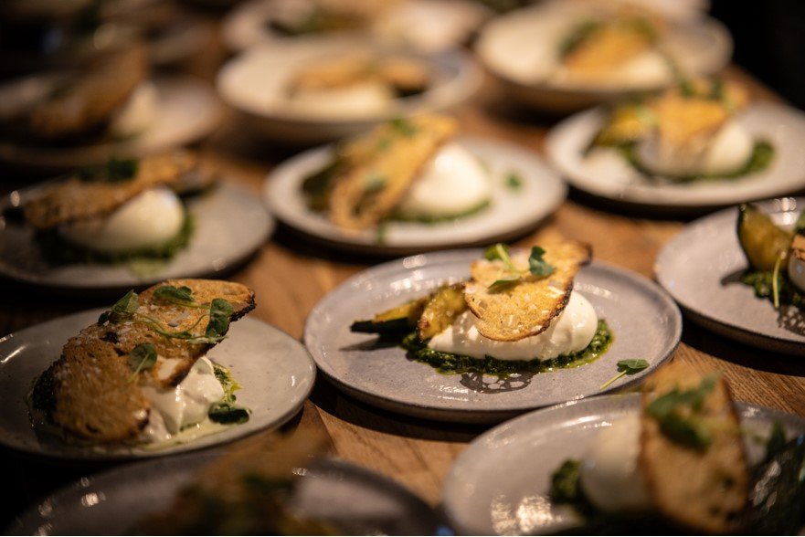 Several plates with toasted bread, poached eggs, green pesto, and garnished herbs