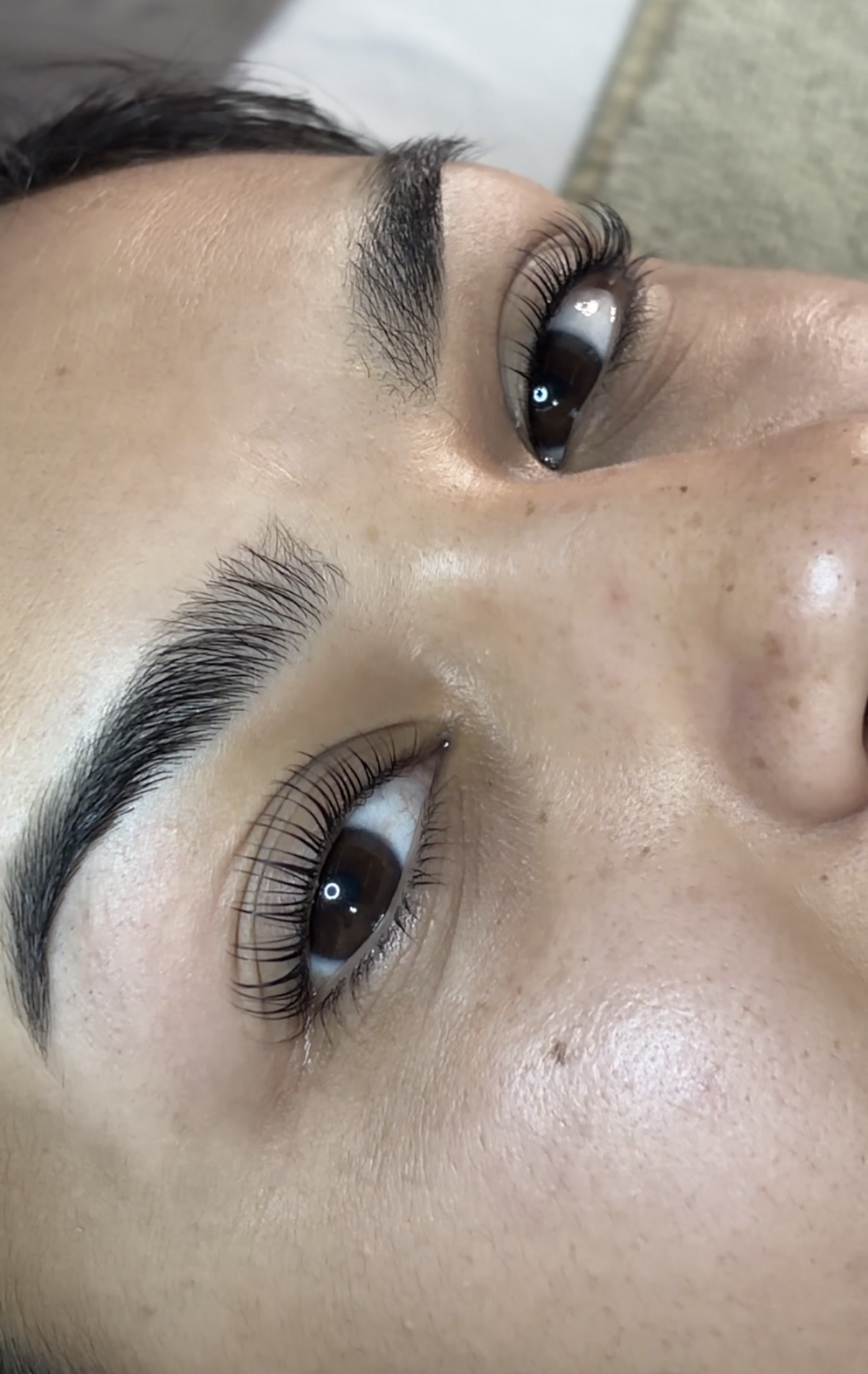 Close-up of a human eye showing greenish-brown iris, long and lifted eyelashes from a lash lift and tint.