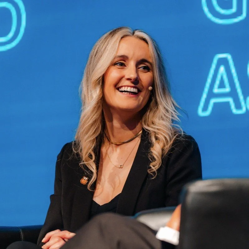 A smiling woman with long blonde hair on a blue background with neon-style text.