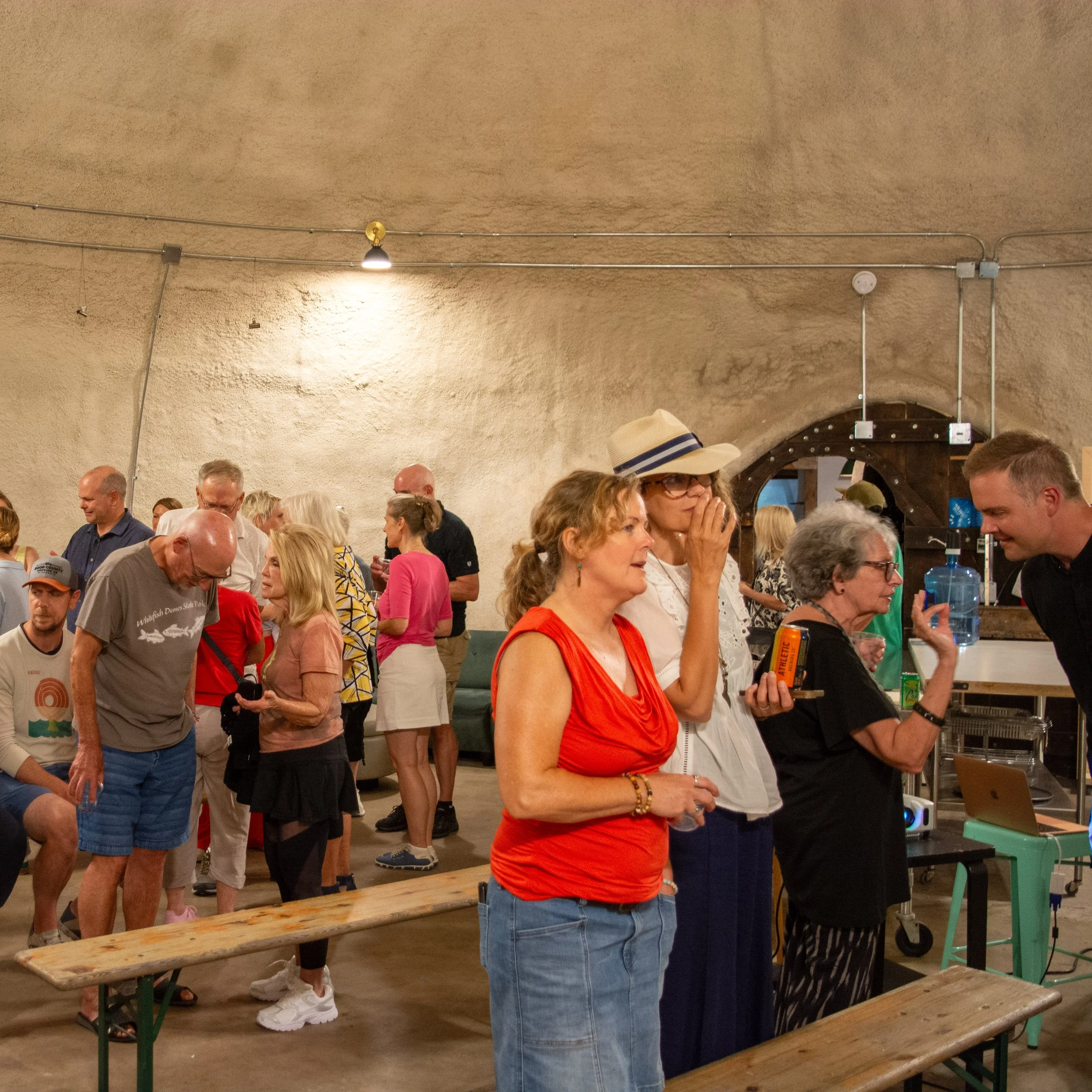 People gathered in a large indoor space, engaging in conversation and activities at a social event.