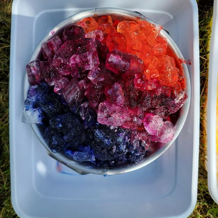 Ice dye in strainer with orange, blue and purple dye