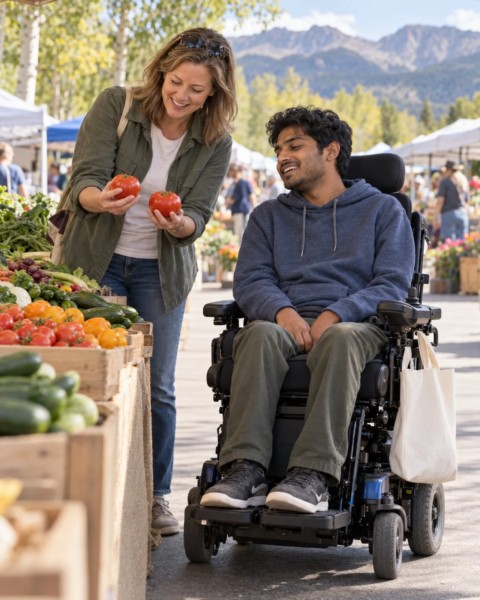 A volunteer and a young man in a power wheelchair choosing tomatoes at a farmers market