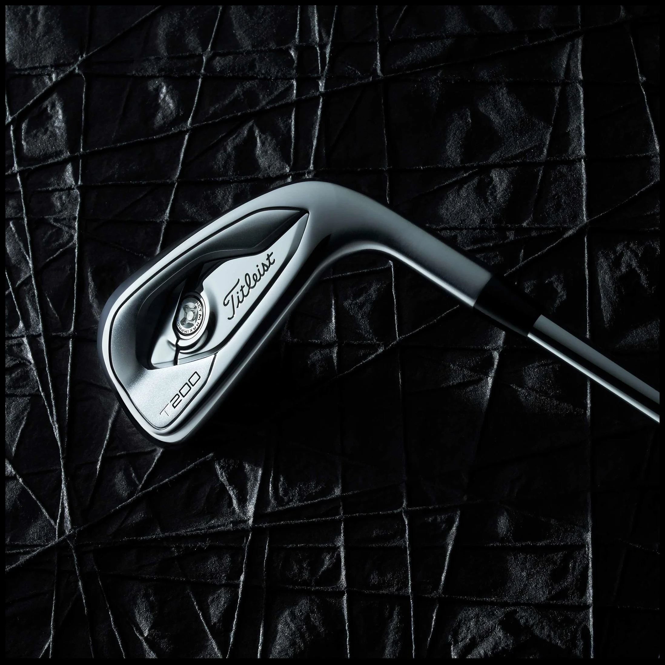 A Titleist T200 golf iron on a black textured surface.  Titleist Golf T200 Golf Iron Black Product Advertising Photography KyleSmithPhoto.