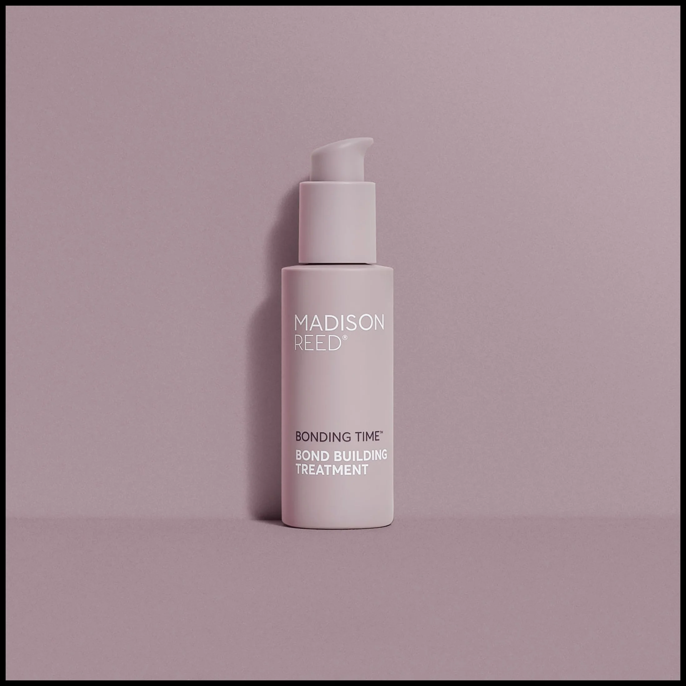 Pink bottle of Madison Reed Bonding Time Bond Building Treatment on a pink background.