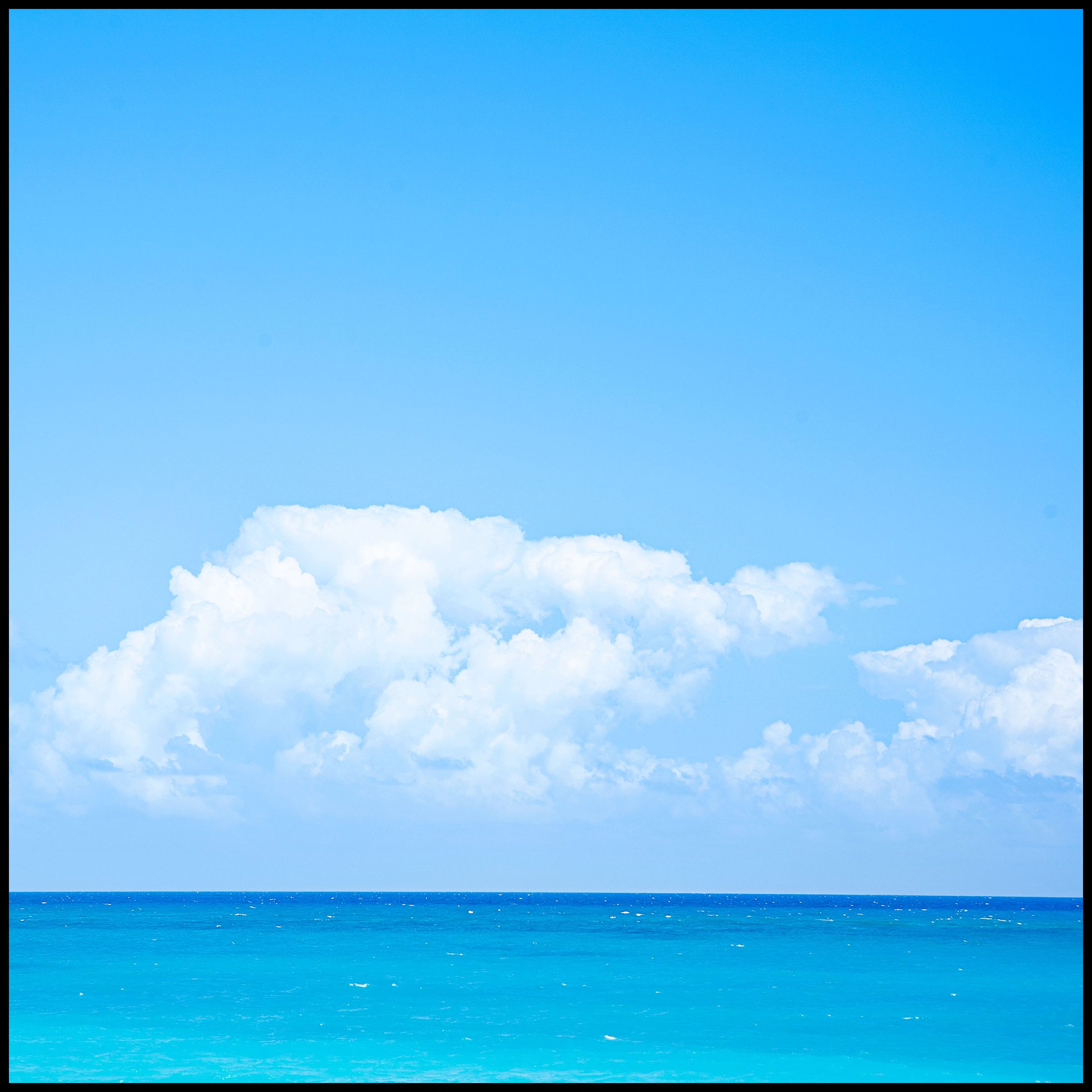 Clear blue sky above the turquoise ocean with white clouds.  Art Prints Isla Mujeres Mexico Island.