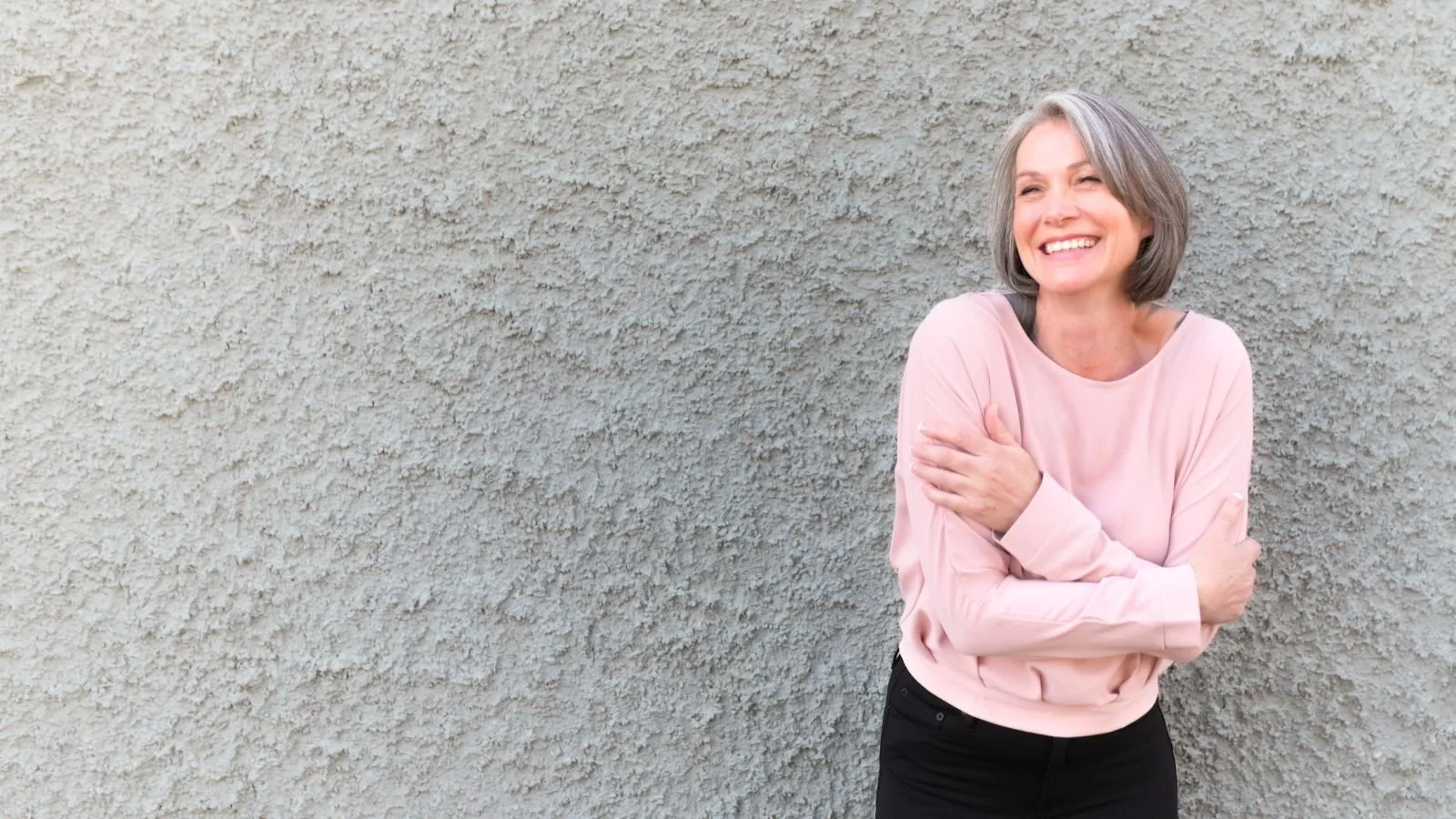 Emma Hull, certified life coach for midlife women, smiling outdoors against a textured wall