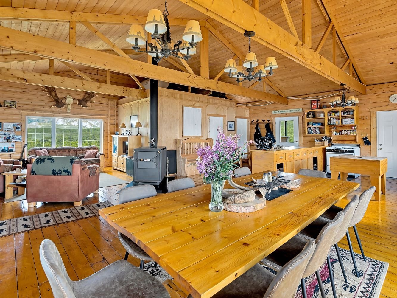 an interior shot of the luxury off-grid Hart Lake Lodge showing a large dining table and cozy wood stove. Hart Lake Yukon is the setting for The Ultimate Couples Retreat