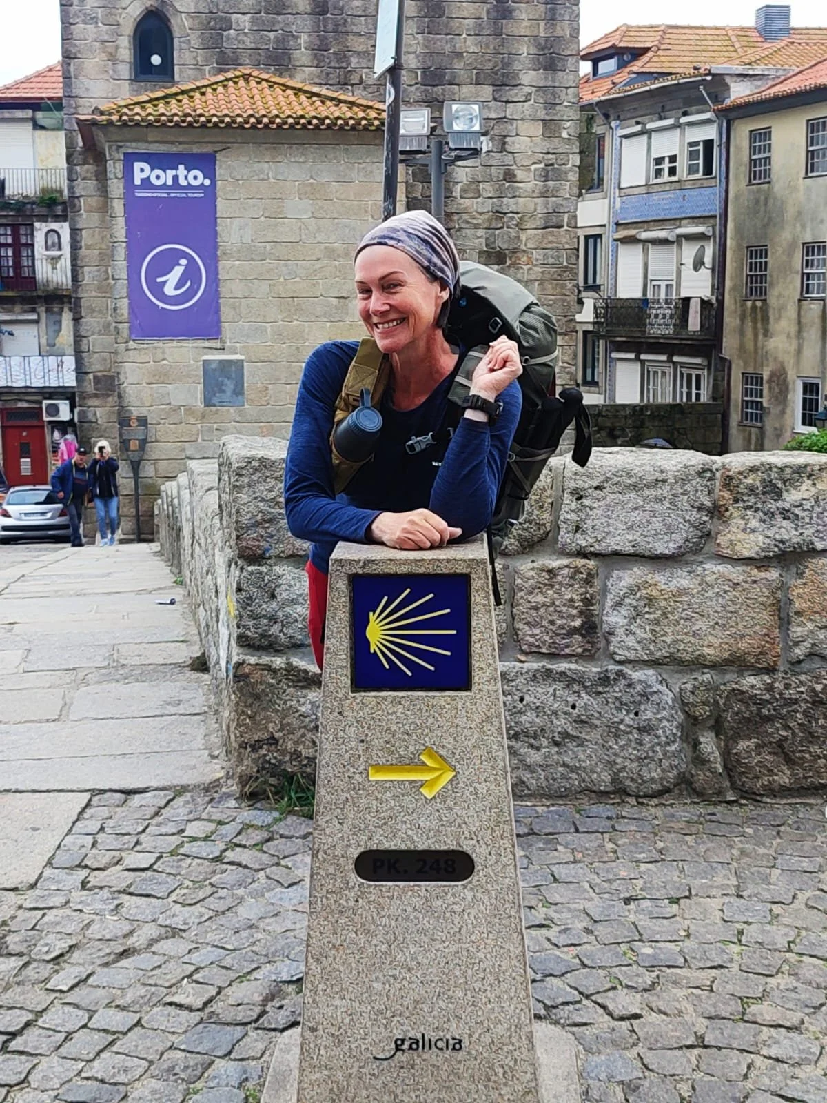 A solo middle aged woman smiling at the start of the Camino de Santiago in Porto, Portugal