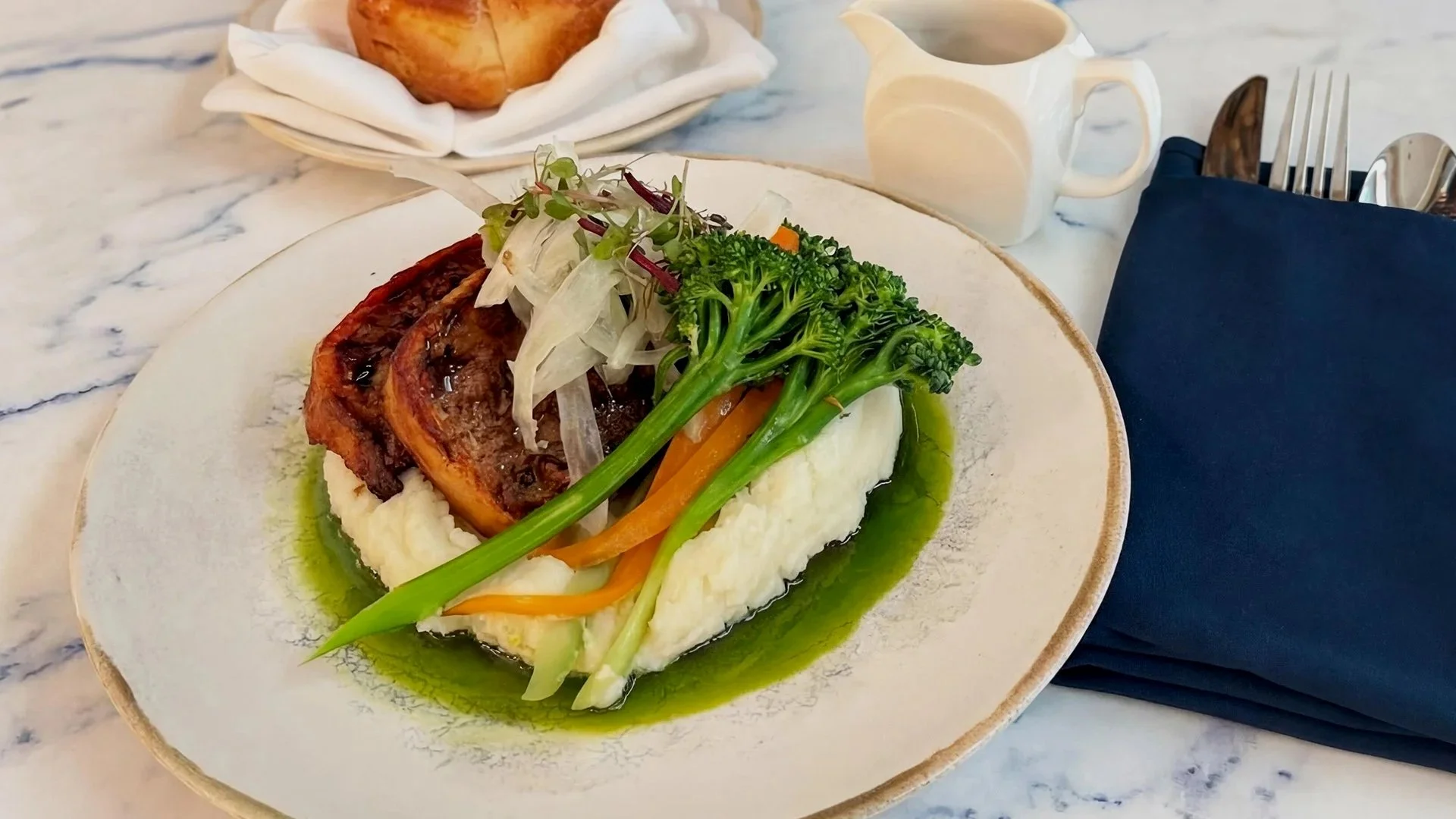 A plate of mashed potatoes topped with roasted meat and vegetables.