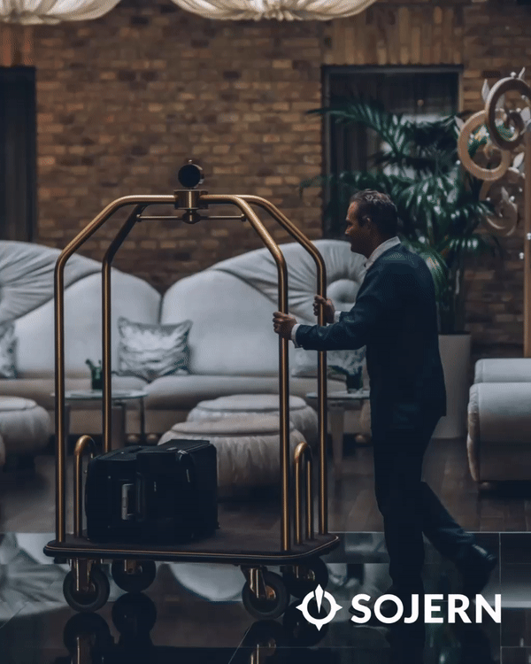 Hotel lobby with a bellhop pushing a luggage cart with suitcases