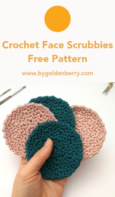 A photo of a white left hand holding 4 round crochet face scrubbies like a hand of cards. 2 are teal and 2 are pastel pink. The background is off white. Above there is orange text which reads "Crochet Face Scrubbies Free Pattern". This is for a pin.