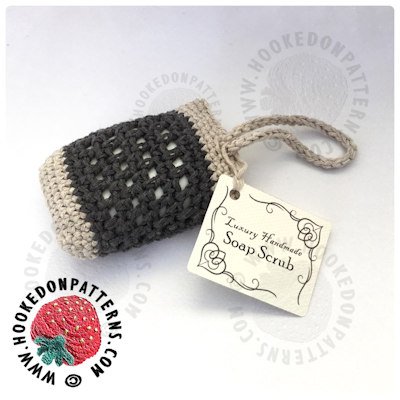 A dark grey and cream soap saver is sat on an off white background. It has a symmetrical pattern of holes around the body and a loop at the top which closes the bag.
