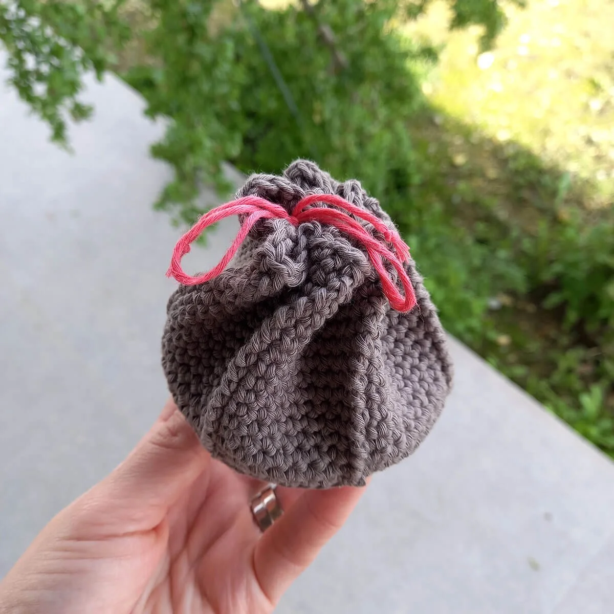 A side angle of the coin purse closed. The hexagonal twist is very clear around the side where some parts fold inwards and the edges of the hexagon stand out in twisted lines from top to bottom.