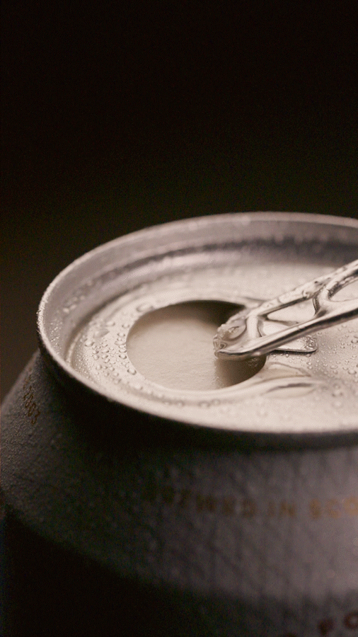 Close-up of an open aluminum beer can with a pull-tab remaining attached, condensation droplets on the can, and a dark background.