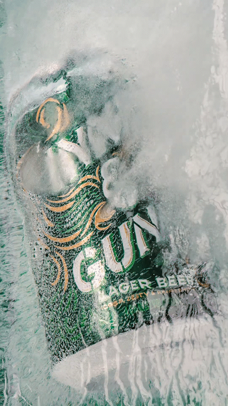 A can of beer with the label 'Gulf' is being underwater with bubbles and water splash around it.