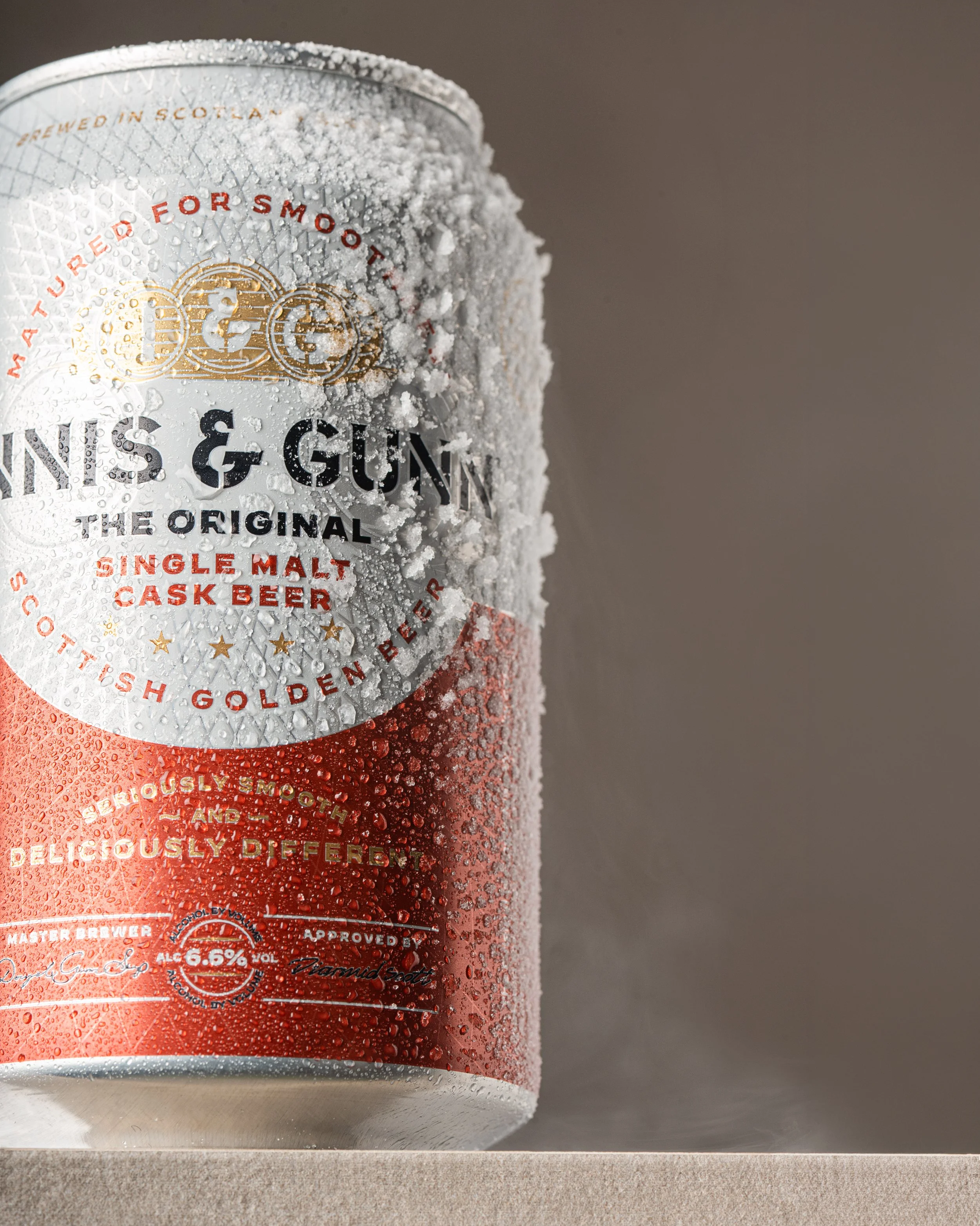 Close-up of a chilled can of Tennent's Guinness & Gunniess beer covered in condensation, placed on a neutral surface.