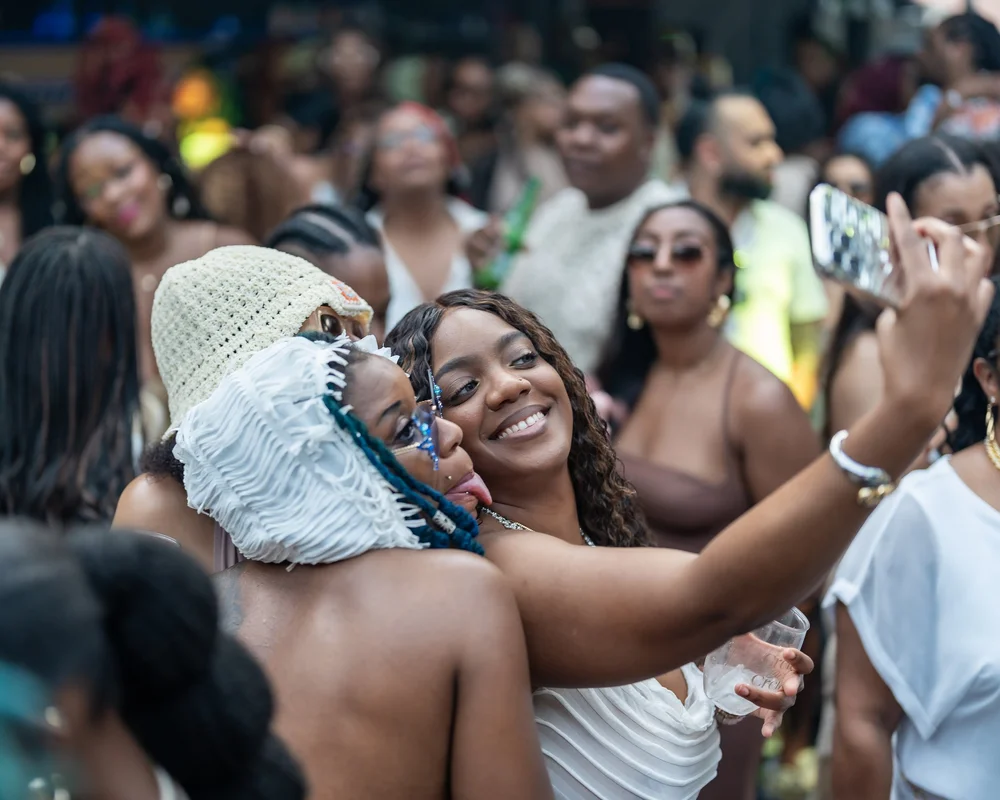 Two friends hugging and laughing at a rooftop day party