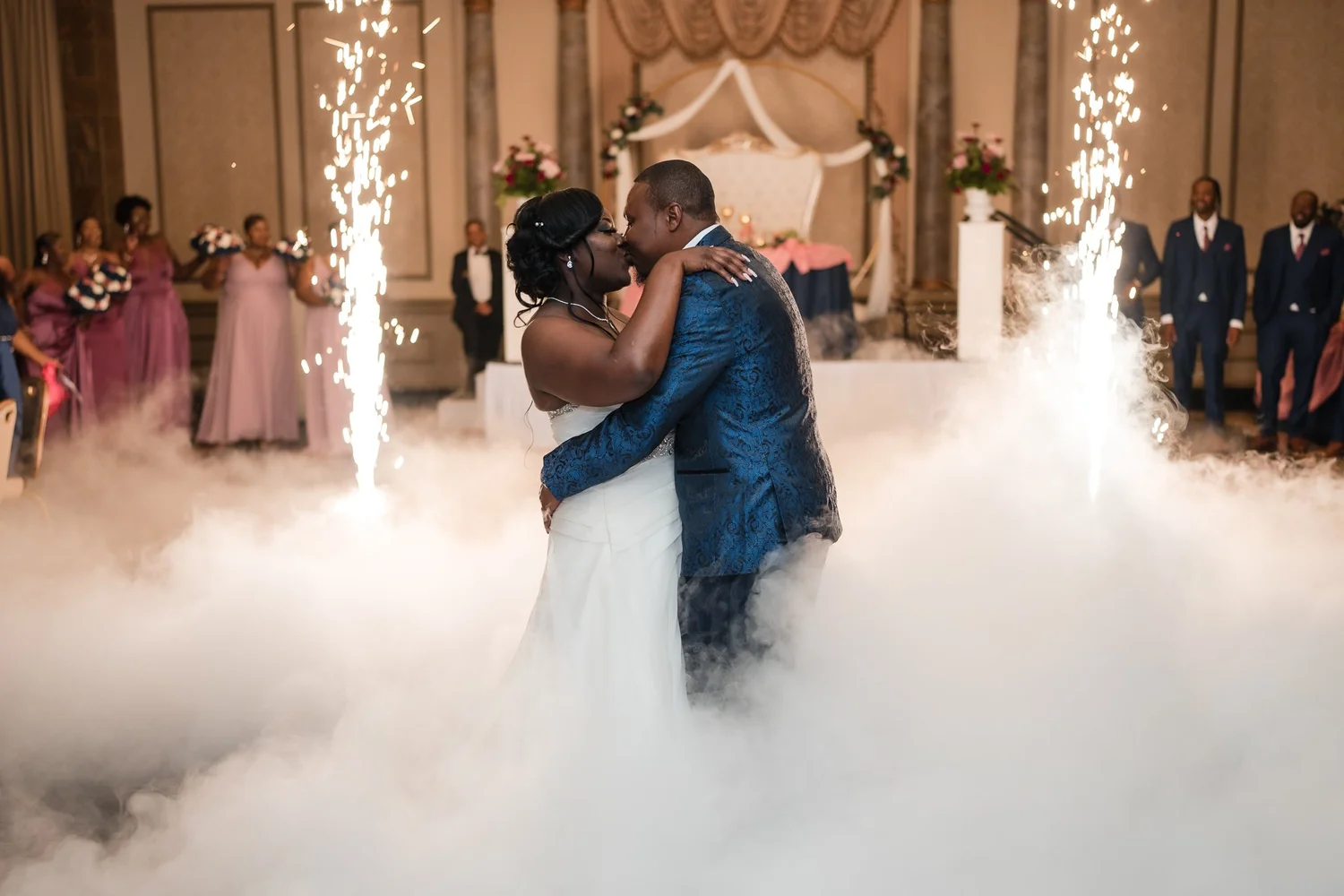 Bride and groom embrace amid cold spark fountains and dry ice fog during their first dance at a Baltimore wedding reception