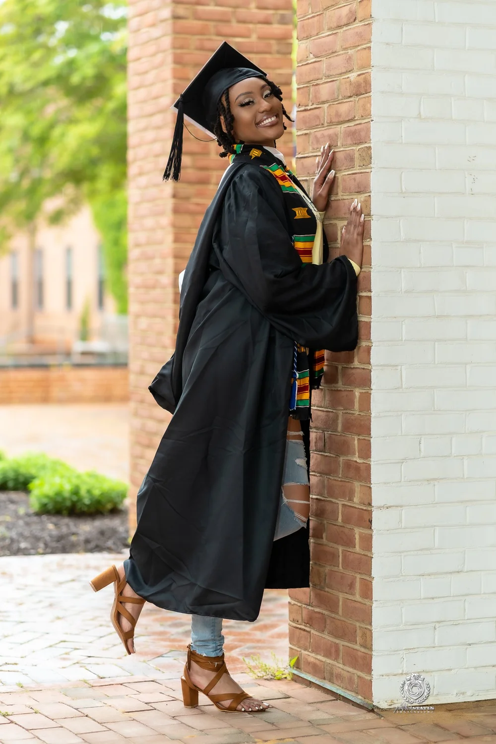 Graduate holding her cap on campus