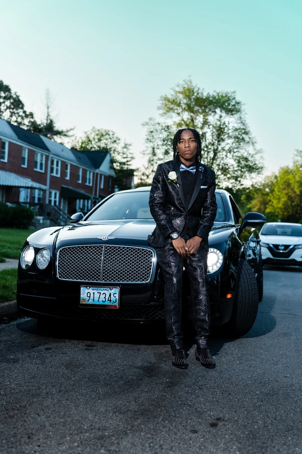 Prom portrait of a young man beside a black car