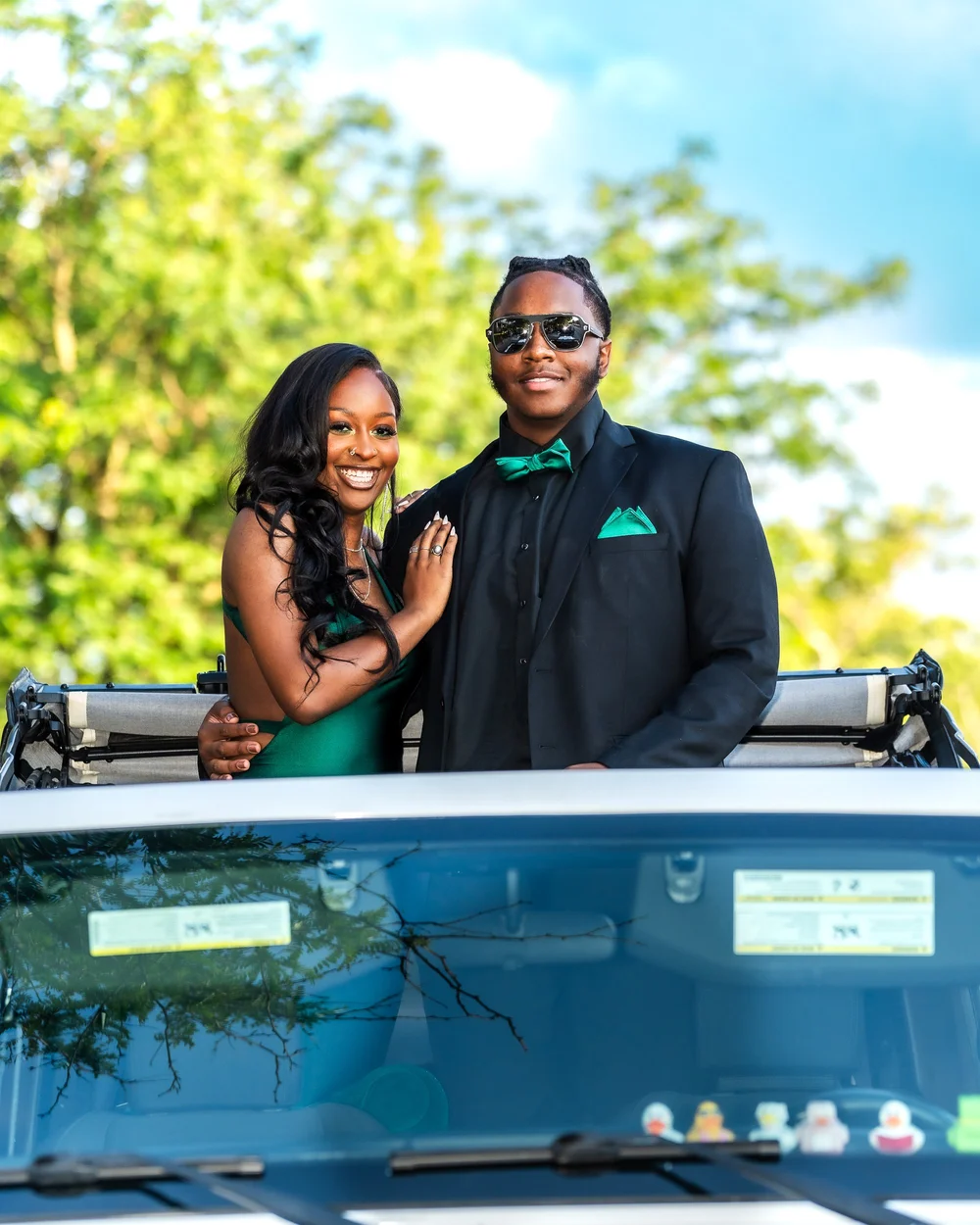 Prom couple posing beside an SUV at their sendoff