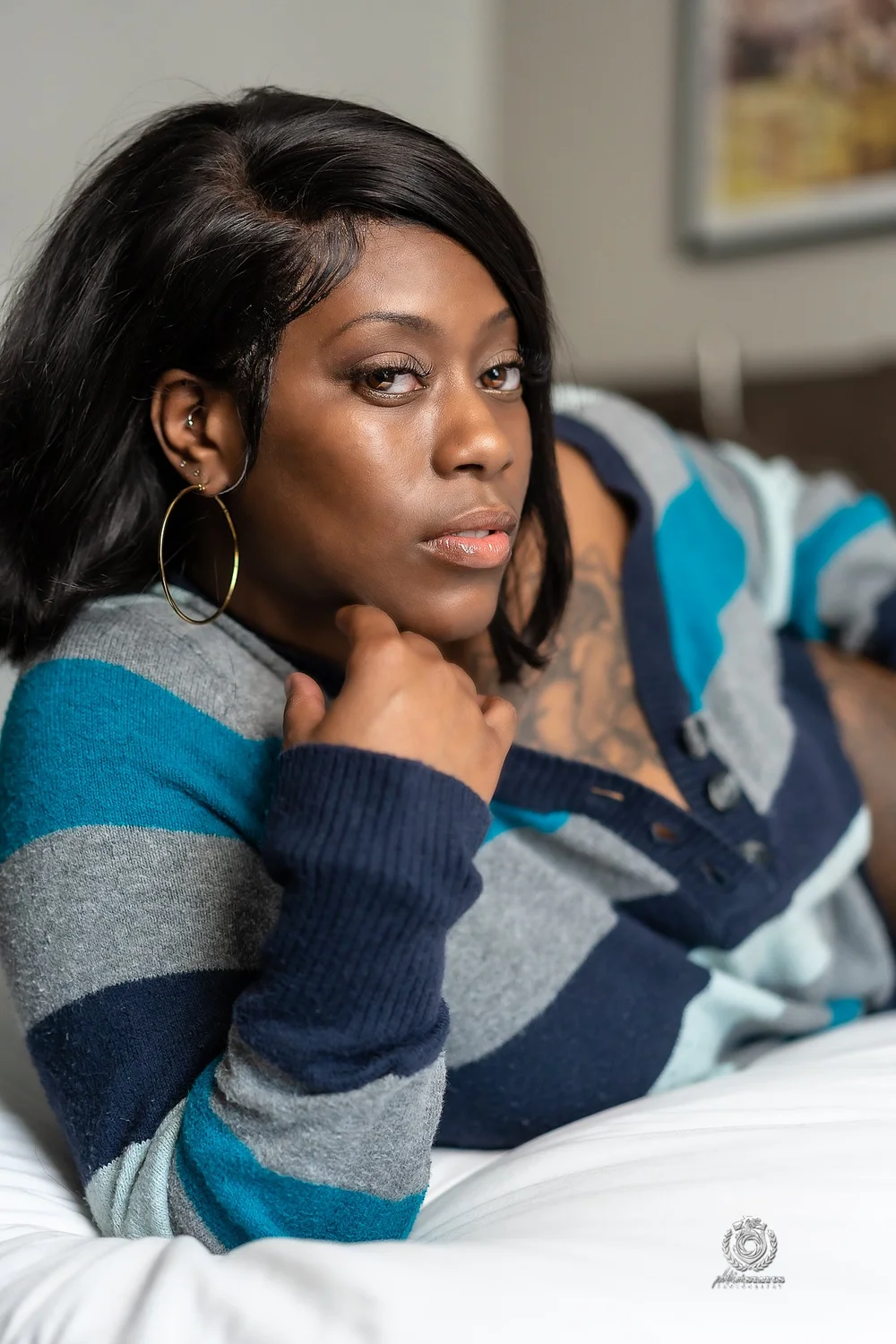 Woman in a striped sweater reclining for a boudoir photography portrait, by Marcus Gregory Photography