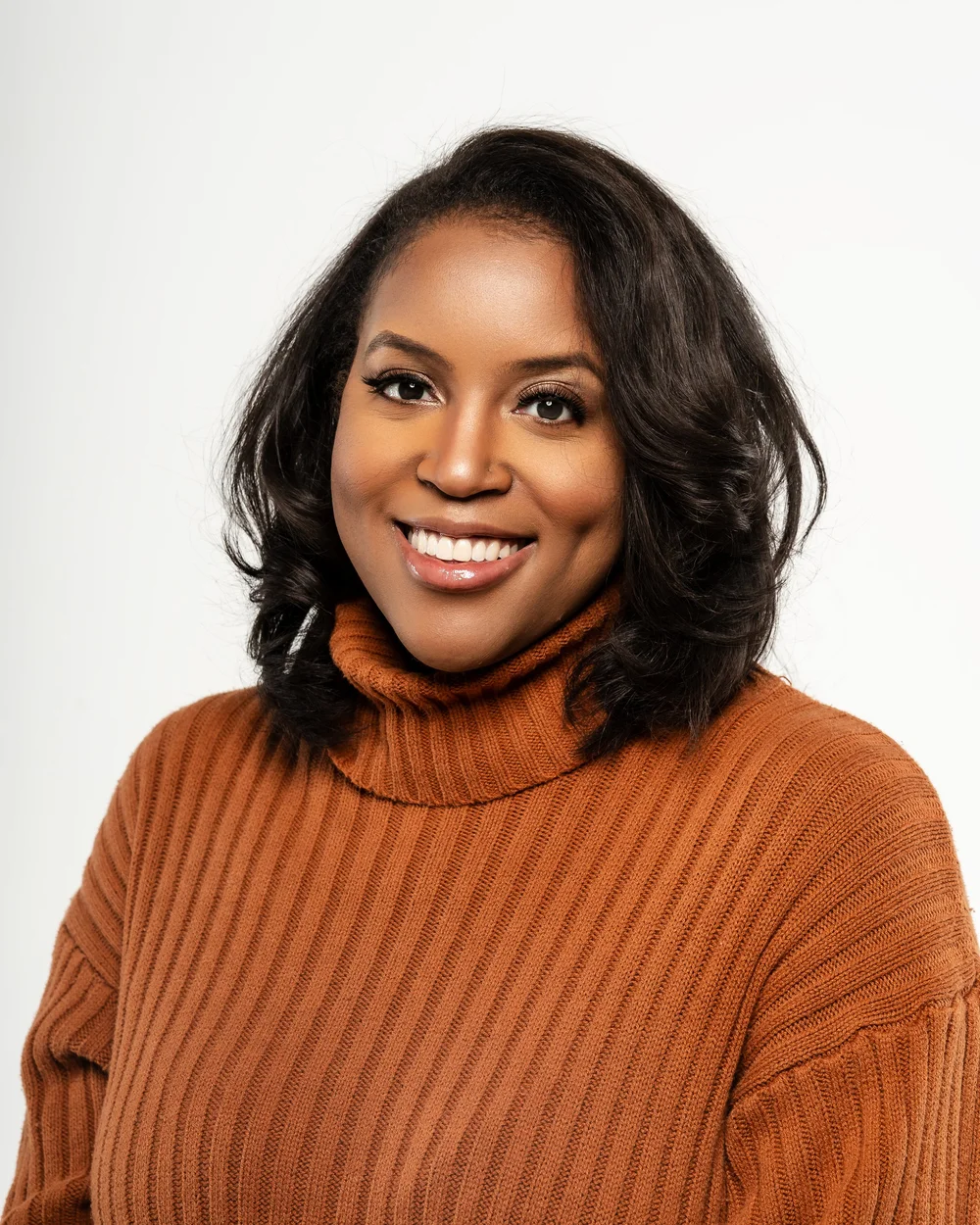 Studio portrait in an orange knit sweater