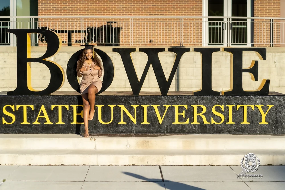 Graduate in a gold dress at the Bowie State University sign