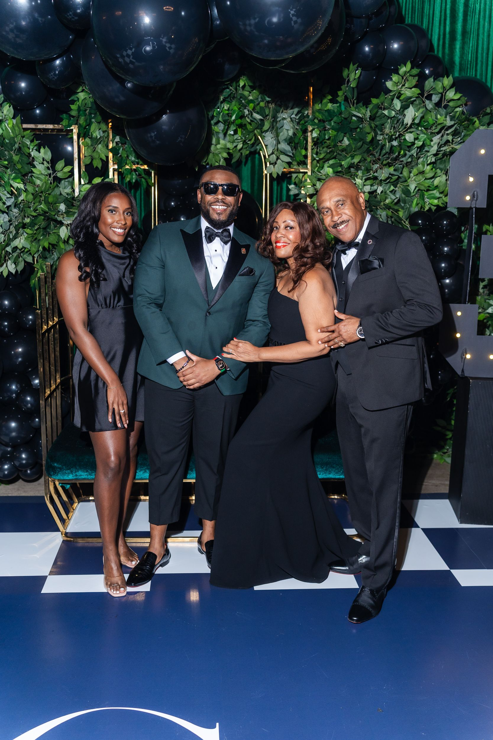Four guests in formal black-tie attire posing together at a Maryland party