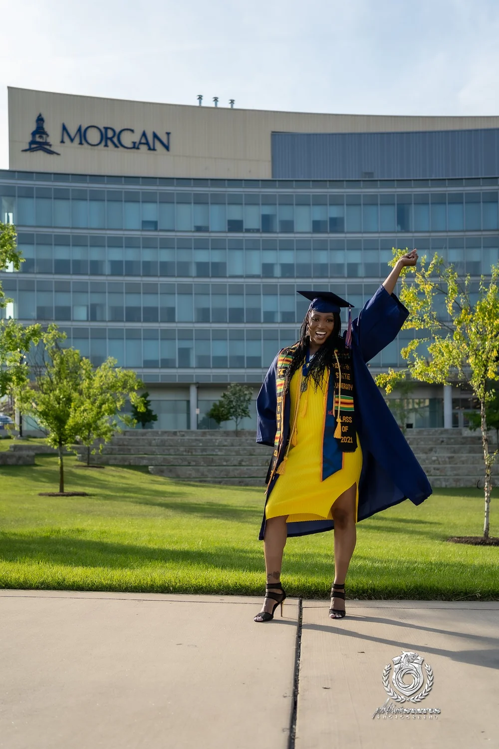 Graduate in cap and gown by a campus building