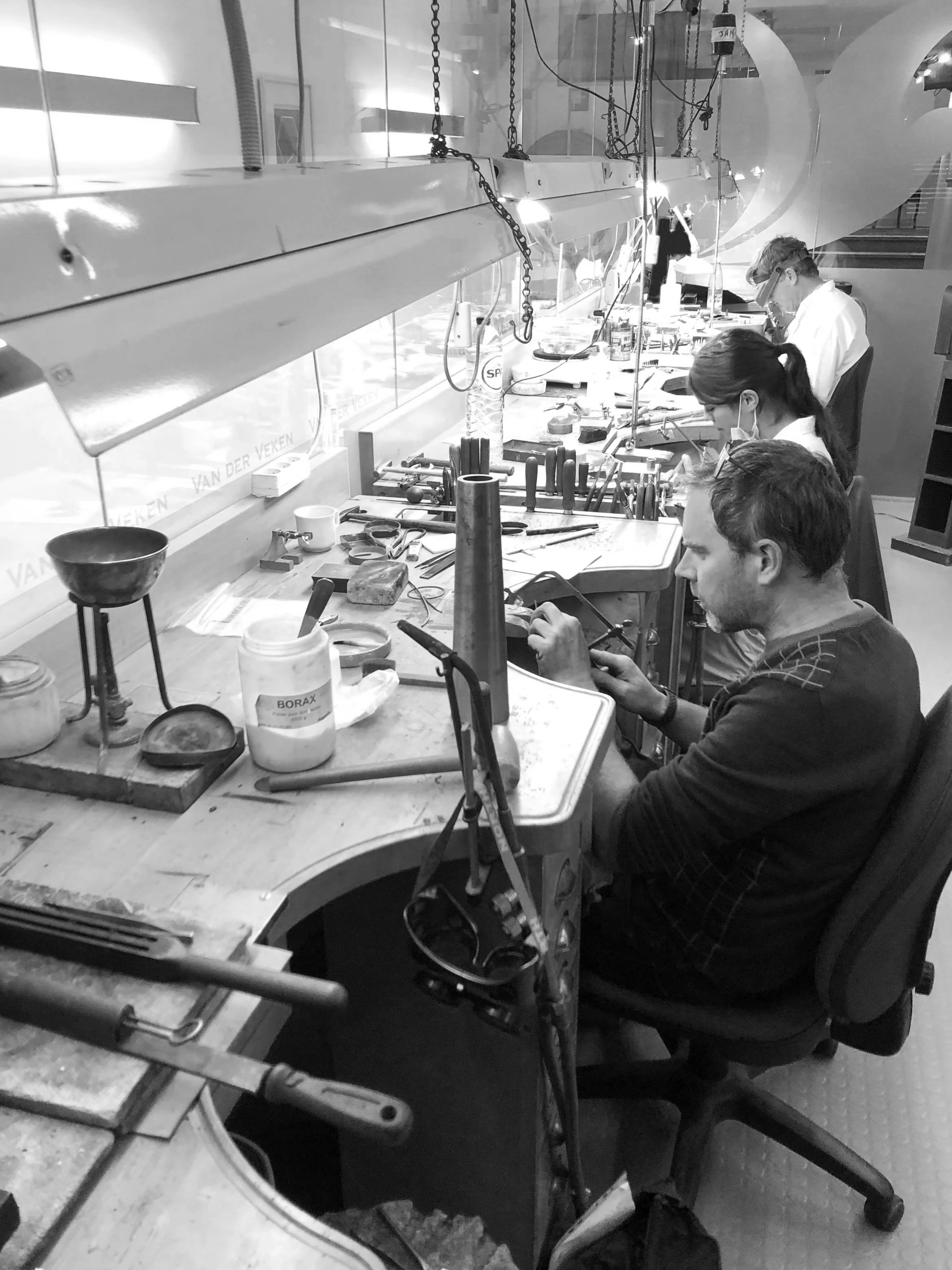 Goudsmeden werken in een atelier met gereedschap en werkstukken.