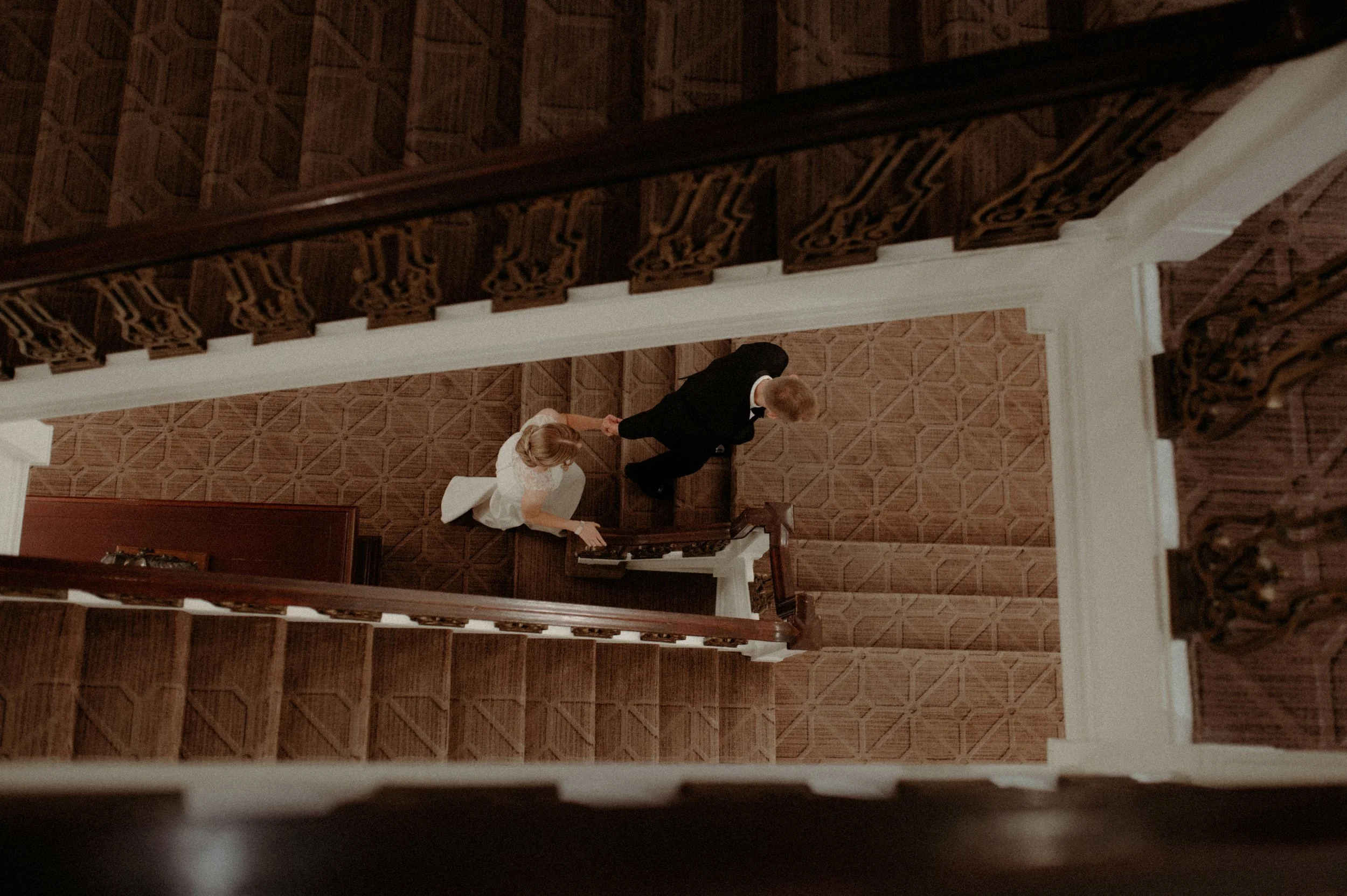 Bride and groom descending a grand wooden staircase, Fairmont Palliser, Alberta wedding photographer