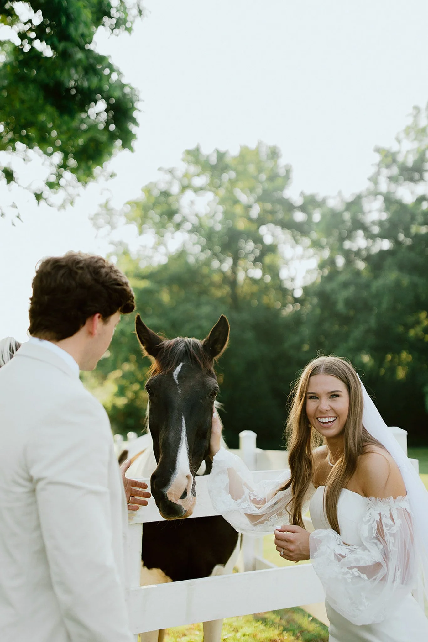 Bride and groom sharing a candid moment with a horse on their wedding day