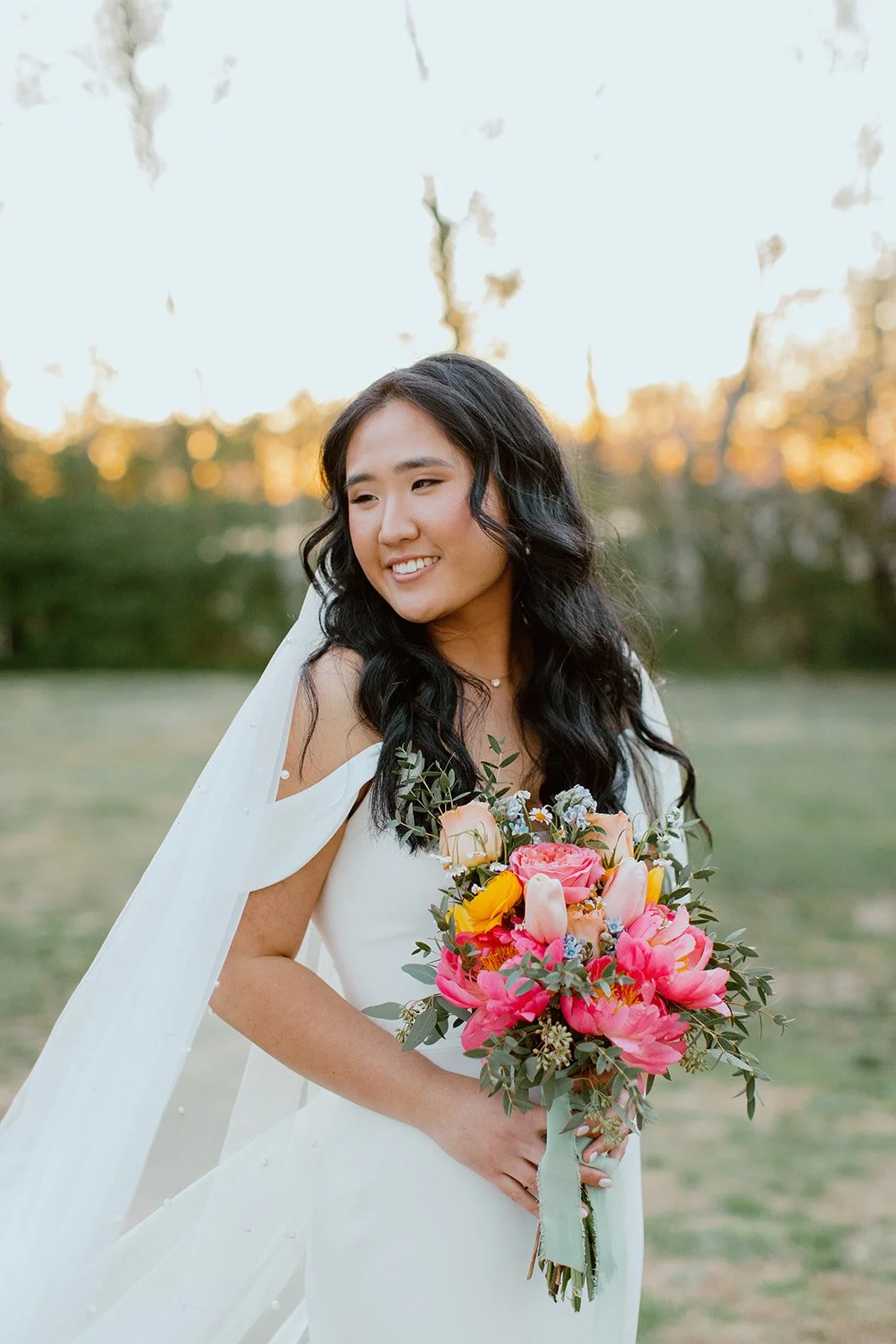 Bride holding a colourful bouquet during a golden-hour wedding portrait