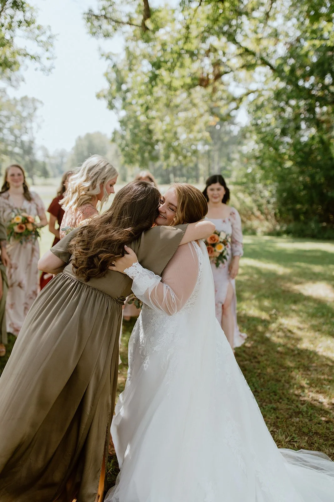 Bride sharing an emotional hug with a wedding guest outdoors