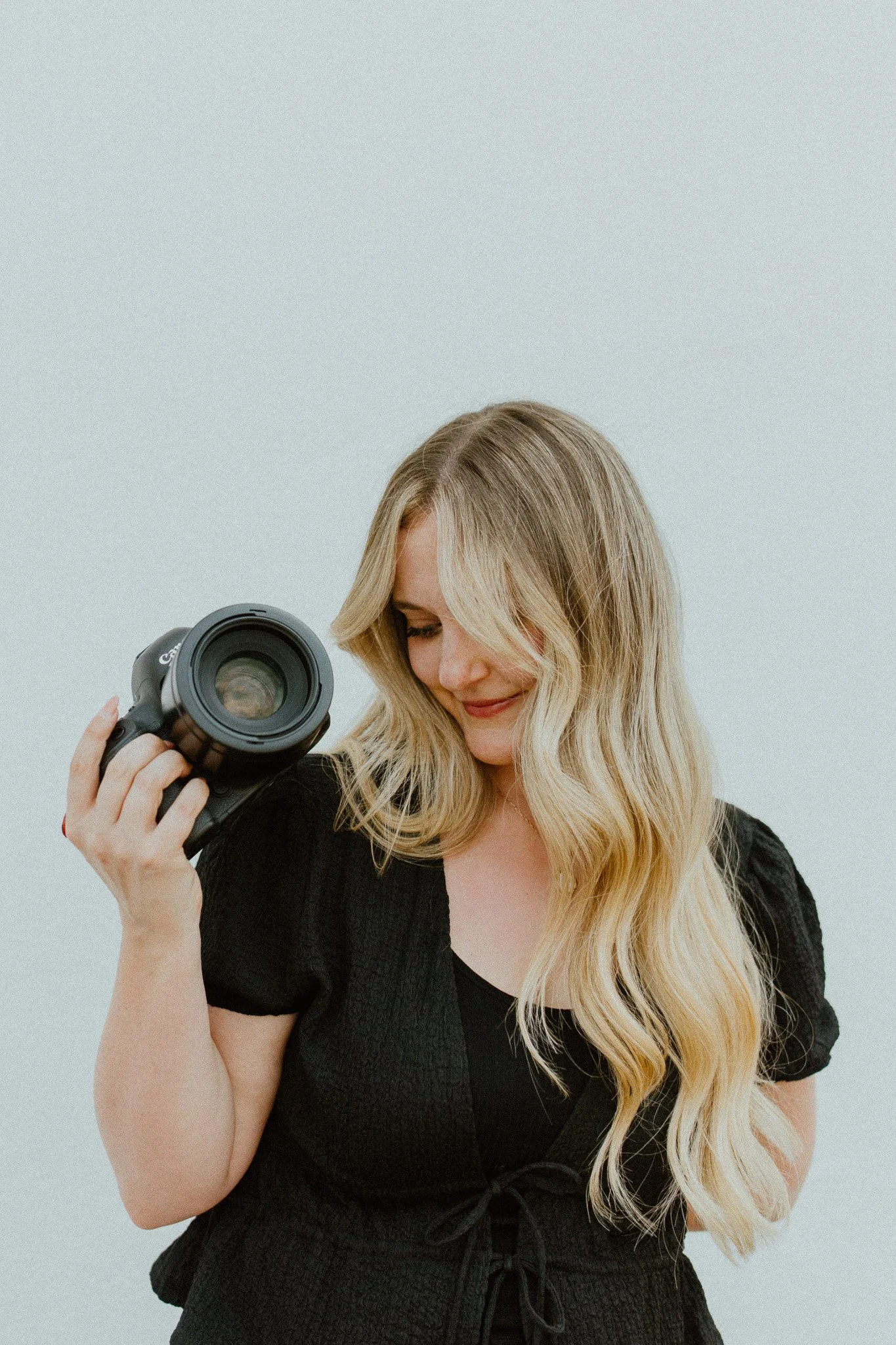 Essex wedding photographer Rachel Marie holding her camera in a relaxed professional portrait.