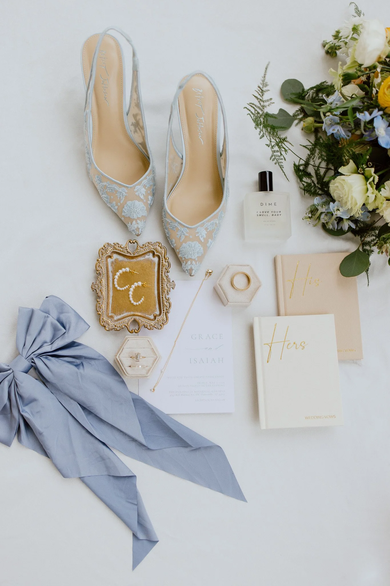 Wedding details with blue bridal shoes, invitations, rings and ribbon