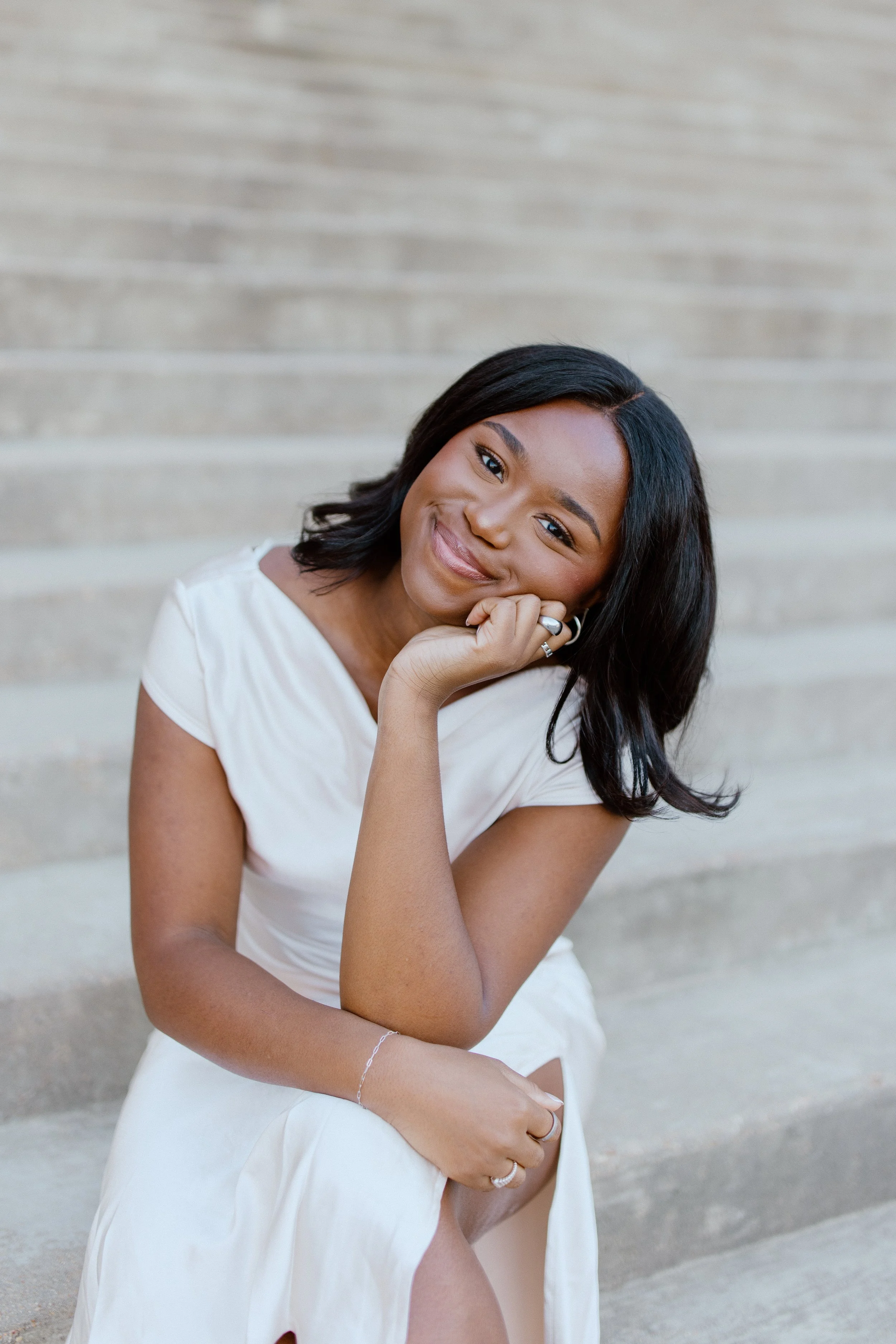 Outdoor portrait of a woman smiling while seated on stone steps at Mississippi State University