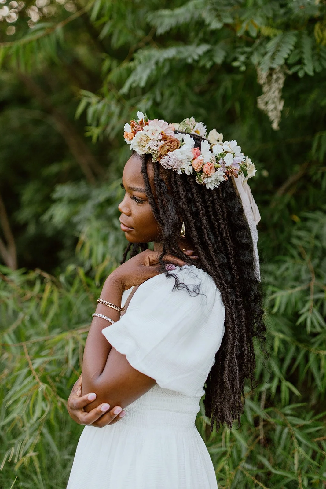 Outdoor portrait of a woman wearing a floral crown surrounded by greenery