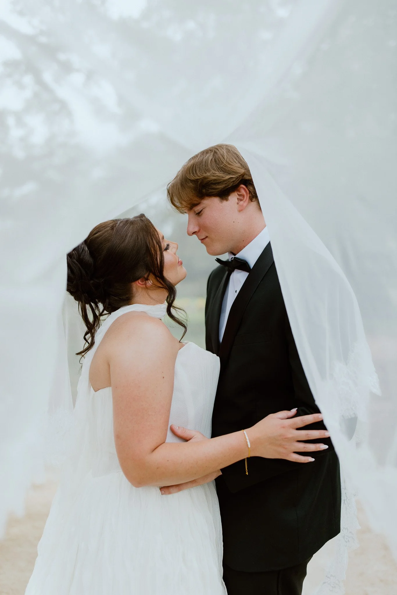 Bride and groom sharing a romantic moment beneath her veil at an Essex wedding.